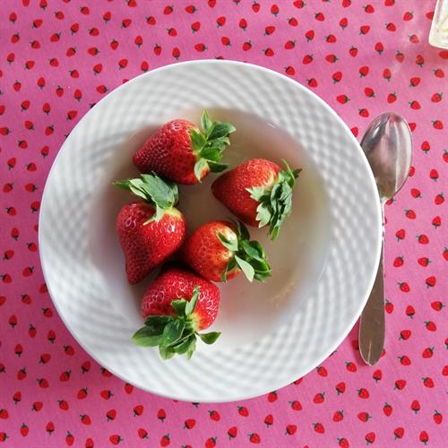 en dejlig skål jordbær på den runde øko voksdug